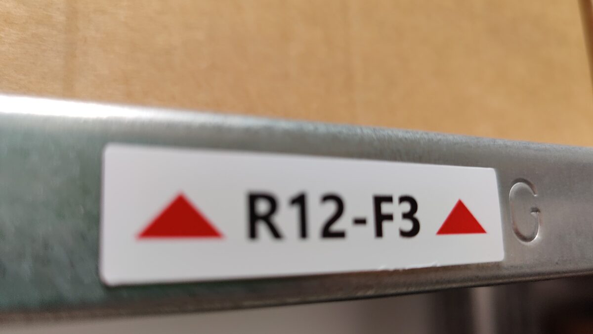 Magnetetikett R12-F3 mit Pfeilen auf der Kante eines Stahlregals